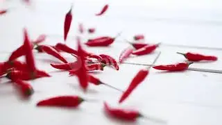 Multiple Red Chili Peppers Falling and Bouncing at White Wooden Table in Slow Motion | Stock Foo...